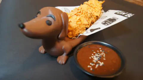 Corn dog Guau con salsa, junto a una figura de perro salchicha